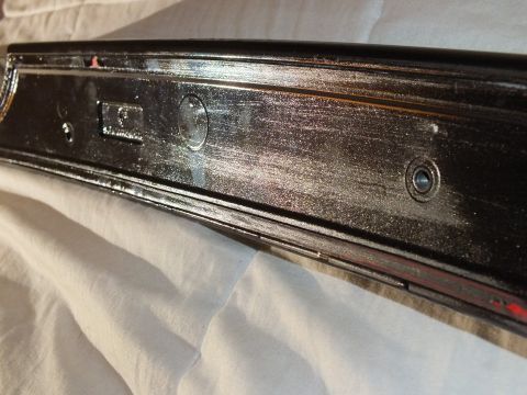 2003 Ford Crown Victoria - Close view of a gloss black trim piece showing its underside, mounting points and threaded studs.