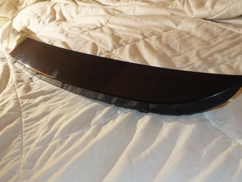 2003 Ford Crown Victoria - slim gloss black spoiler-style trim piece rests curved across a white quilt.