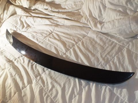 2003 Ford Crown Victoria - Long curved black trim spoiler resting across a softly lit white quilted bed.