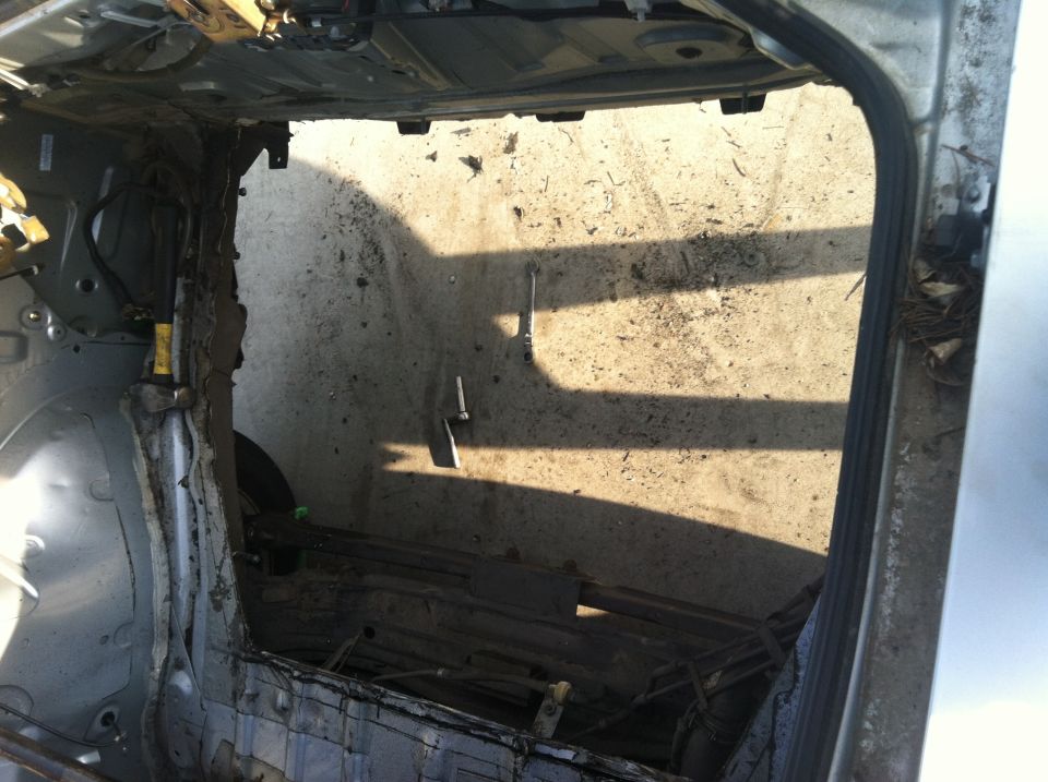 Interior of a car with significant damage to the rear passenger side, exposing structural components