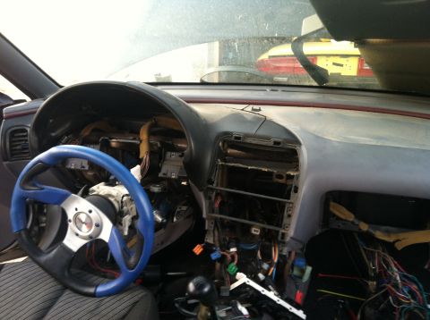 1993 Ford Probe - The dashboard of a car is dismantled, revealing wires and components, with another car visible outside.