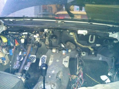 1993 Ford Probe - The dashboard is removed, revealing the car's internal wiring and components. The pedals are visible, suggesting a manual transmission.