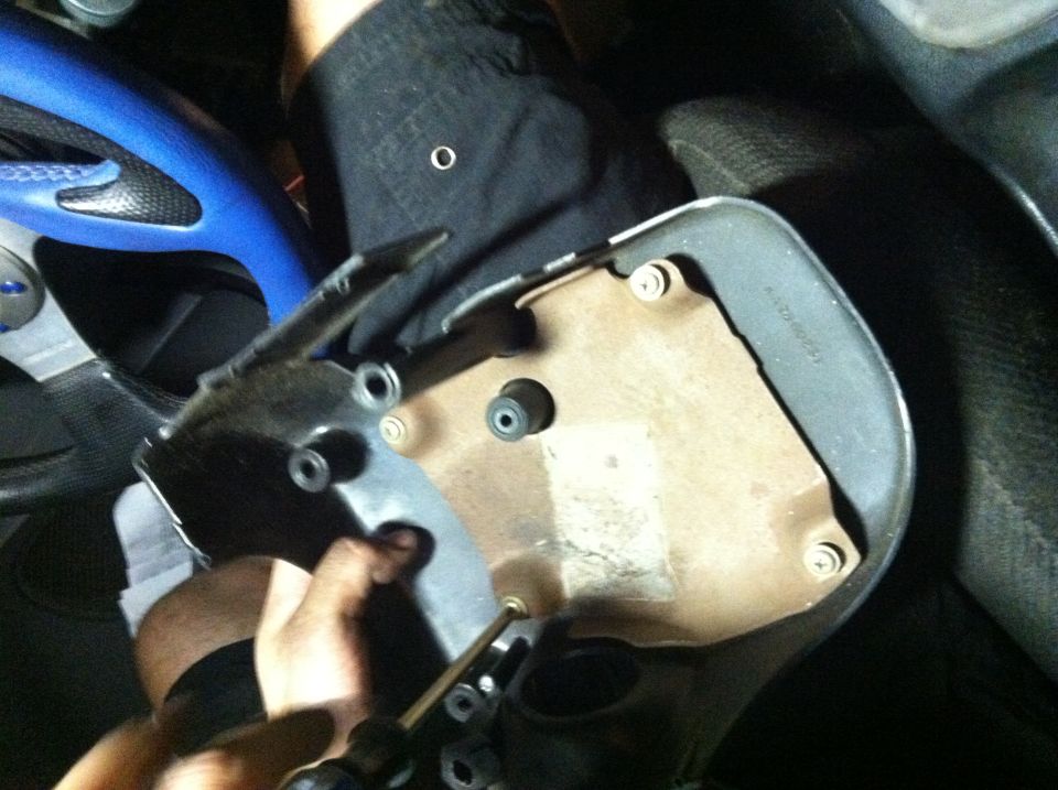 Car interior part being worked on with a screwdriver. Blue and black steering wheel visible