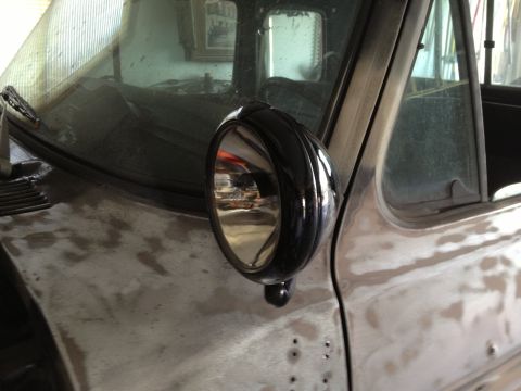 1979 Ford F-350 - Close-up of a black side mirror mounted on a truck's fender, showing the vehicle's unfinished bodywork.