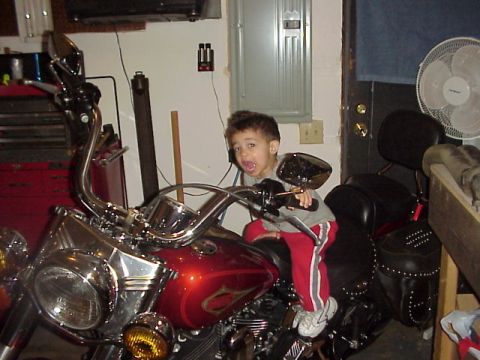 1989 Ford Bronco - A young child sits on a motorcycle in what appears to be a garage or workshop.