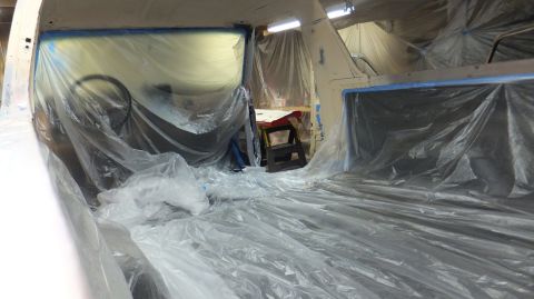 1983 Ford Bronco - Interior of a vehicle being prepped for painting, with plastic sheeting covering most surfaces.