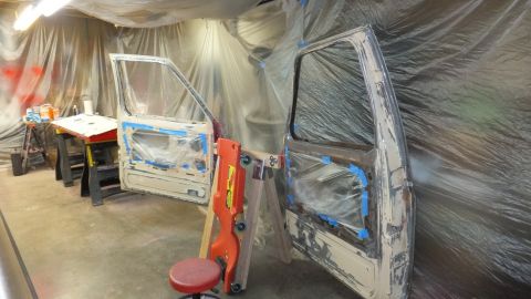1983 Ford Bronco - Vehicle doors are prepped for work in a plastic-draped garage, with tools and supplies nearby.