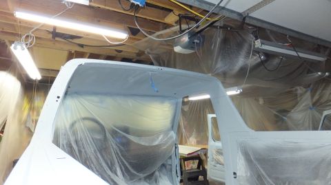 1983 Ford Bronco - Body of a 1983 Ford Bronco is covered in plastic for paint preparation in a garage.