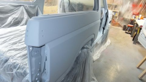 1983 Ford Bronco - The body of a Ford Bronco is prepped for paint, with doors removed and covered in plastic sheeting.