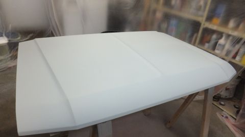 1983 Ford Bronco - Car hood prepared for painting in a workshop environment.
