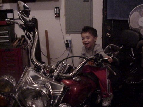 1989 Ford Bronco - A young child sits on a motorcycle, smiling broadly.