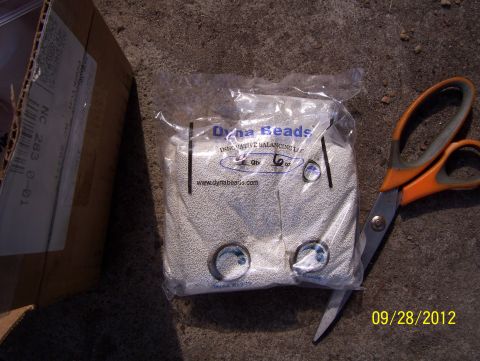 1990 Ford Bronco - A bag of Dyna Beads and a pair of scissors sit on a rough surface next to a cardboard box.