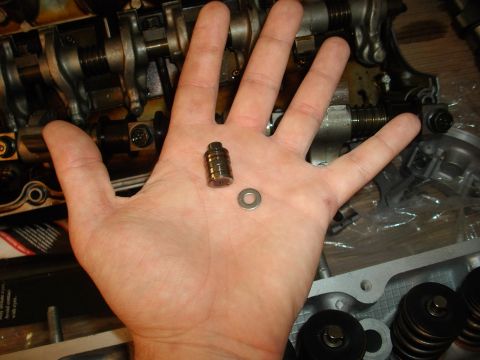 1989 Ford Probe - Engine parts, including a valve lifter and washer, are held in a hand during a repair.