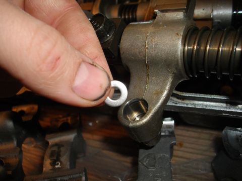 1989 Ford Probe - Close-up of a hand holding a washer near an engine's rocker arm assembly.