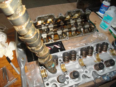 1989 Ford Probe - Disassembled engine cylinder head components, including camshaft and valve springs, are laid out on a surface with tools.