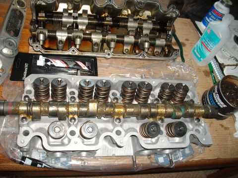 1989 Ford Probe - Disassembled engine cylinder head components are laid out on a wooden surface with repair supplies.