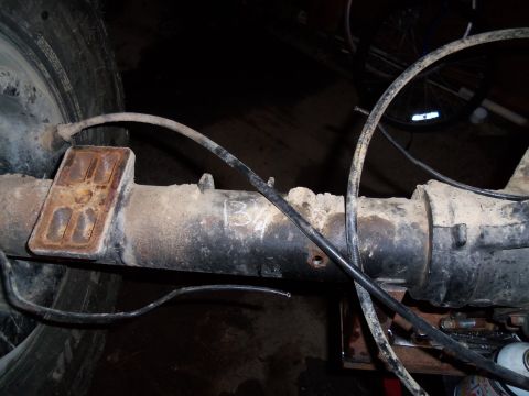 1989 Ford Bronco - The rear axle assembly is covered in dirt and grime, with brake lines running along its length.
