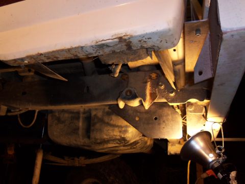 1989 Ford Bronco - Close-up of the rear suspension and fuel tank area of a vehicle, with a work light illuminating the components.