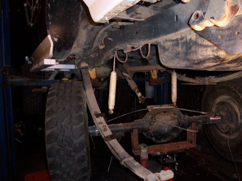1989 Ford Bronco - Close-up view of the rear suspension components of a vehicle, including the axle and leaf springs.