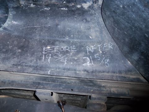 1989 Ford Bronco - Measurements written in chalk on the underside of a vehicle indicate changes before and after a modification.