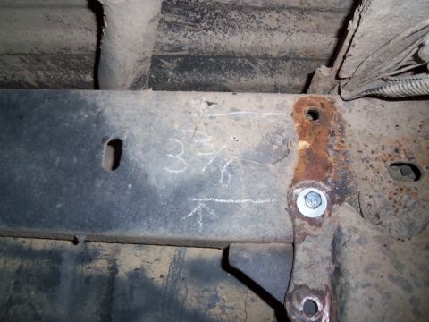1989 Ford Bronco - Close-up of vehicle frame with chalk measurements, indicating a part of the rear suspension.