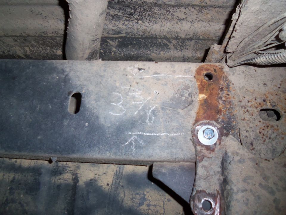 Rusty metal frame with chalk markings '3 7/16' and an arrow