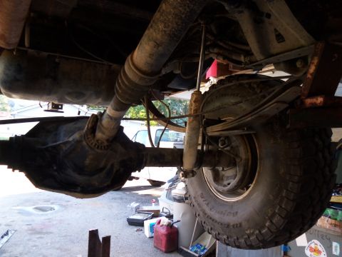 1989 Ford Bronco - The rear suspension and axle assembly of a vehicle are shown from underneath, with a fuel tank overhead.