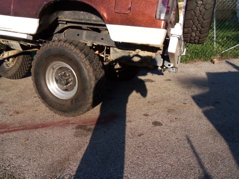 1989 Ford Bronco - The rear suspension and large tire of a 1989 Ford Bronco are visible in this photo.
