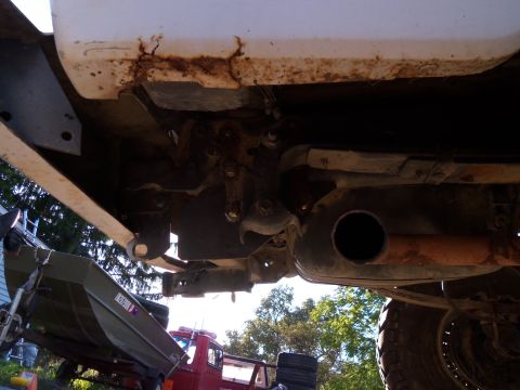 1989 Ford Bronco - Underside view of vehicle rear suspension and exhaust system, showing rust on the frame.