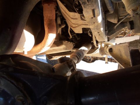 1989 Ford Bronco - The photo shows the undercarriage of a vehicle, focusing on the drivetrain components and exhaust system.