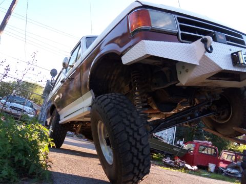 1989 Ford Bronco - This lifted Ford F-Series truck features a custom diamond plate bumper and large off-road tires.