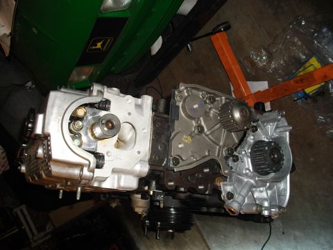 1989 Ford Probe - Disassembled engine block with gears and pulleys visible, next to a green tractor hood.
