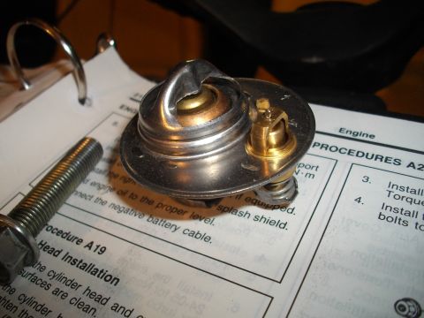 1989 Ford Probe - A car thermostat sits on a page from a service manual detailing engine procedures.