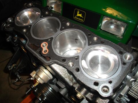 1989 Ford Probe - Engine block with pistons and gasket, with a green John Deere tractor in the background.