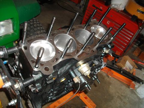 1989 Ford Probe - Engine block with pistons and valves exposed, mounted on an orange engine stand in a workshop.