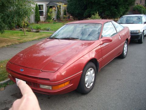 1989 Ford Probe - A red 1989 Ford Probe is parked on a residential street next to a white car.
