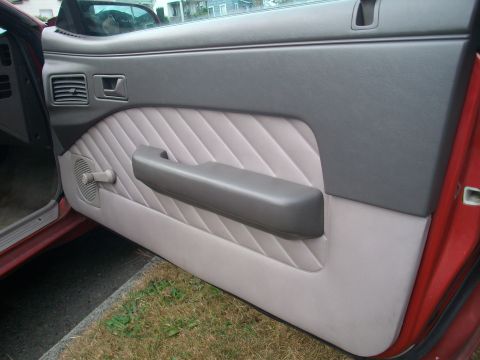 1989 Ford Probe - Close-up of a car's interior door panel, showing the textured fabric and armrest detail.