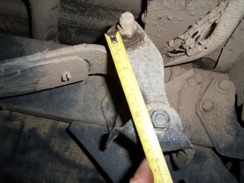 1989 Ford Bronco - A close-up view of a suspension component being measured, showing rust and dirt accumulation.