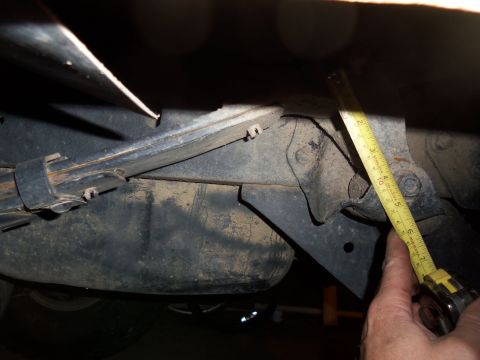 1989 Ford Bronco - Close-up of vehicle's undercarriage shows suspension components and a tape measure for scale.