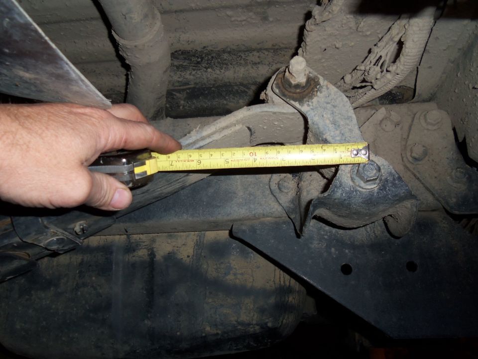 Measuring rear suspension component with a yellow tape measure