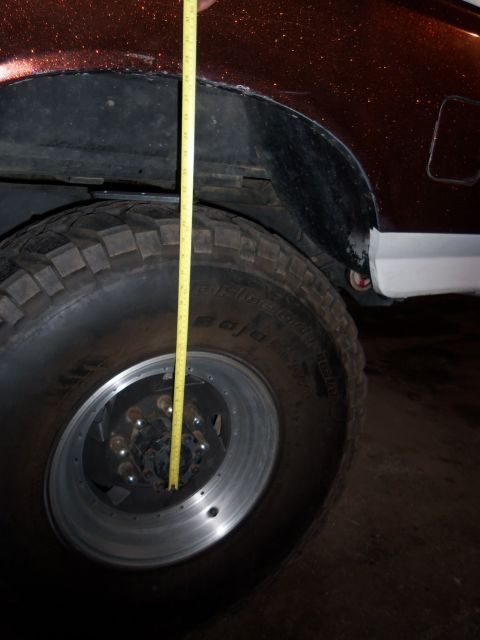 1989 Ford Bronco - A yellow measuring tape is held vertically against the wheel well of a vehicle.