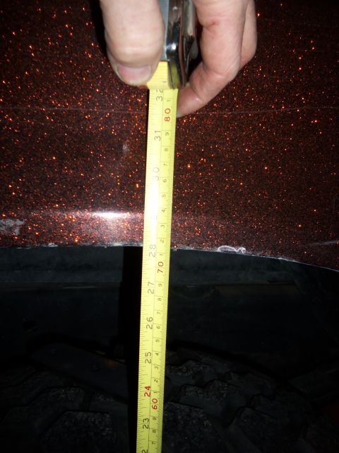 1989 Ford Bronco - A measuring tape is held against the fender of a vehicle with a glittery orange paint job.