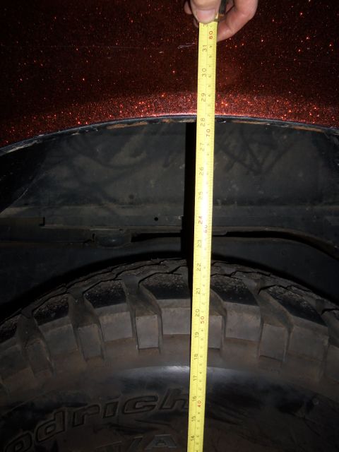 1989 Ford Bronco - A tape measure is used to check the clearance in the rear wheel well of a vehicle.