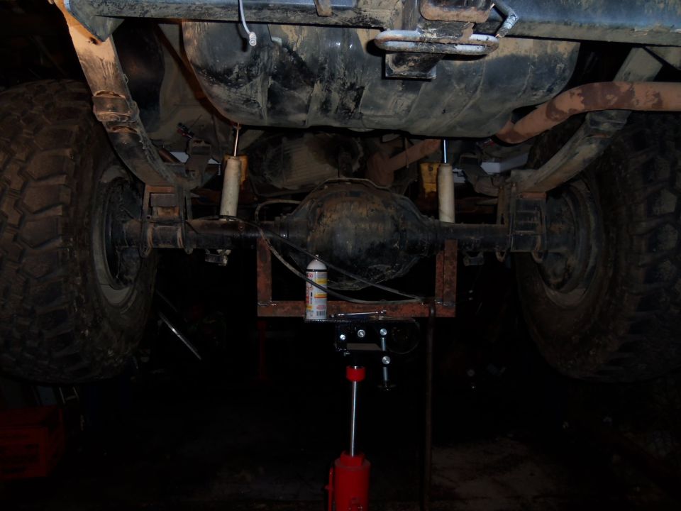 Rear axle assembly with leaf springs and shock absorbers, supported by a red jack