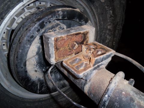 1989 Ford Bronco - A close-up view of a rusty rear suspension component, likely from a vehicle, showing wear and tear.