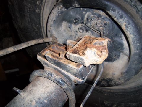 1989 Ford Bronco - Close-up of a rusted suspension part, possibly a bump stop, near a tire.
