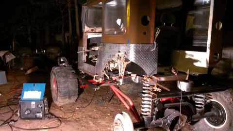 1978 Ford Bronco - A custom off-road vehicle is being worked on at night, with a welder connected to it.