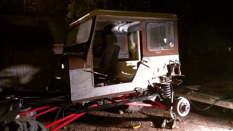 1978 Ford Bronco - A vehicle chassis with a cab is shown with its suspension exposed and diamond plate side panels.