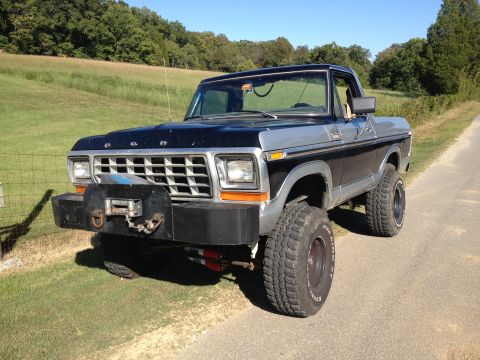 1979 Ford Bronco - A black and silver 1978 Ford Bronco is parked on a dirt road with a grassy field in the background.