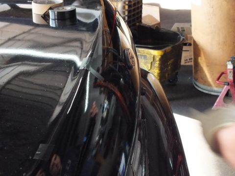 2003 Ford Crown Victoria - Detail of a black sedan's rear deck and quarter panel with masking tape and a jack stand nearby.